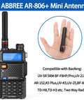 Person holding a black ABBREE AR-806+ mini antenna next to a Baofeng radio, showing compatibility with various models.