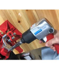Premium 1/2 Inch Drive Pneumatic Impact Wrench in action, gripping rusted bolts on a red work bench for tough automotive jobs.