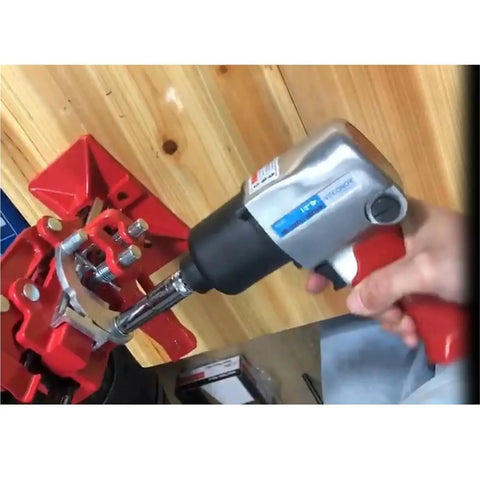 Premium 1/2 Inch Drive Pneumatic Impact Wrench in action, gripping rusted bolts on a red work bench for tough automotive jobs.