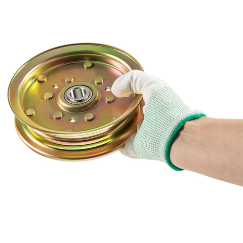 Front view of a gold metal idler pulley assembly with bearing, held by a white-gloved hand.