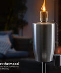 Close-up of stainless steel outdoor torch with lit flame and snuffer cap, part of 5 ft citronella oil lamp set for backyard.