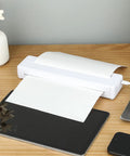 Slick Wireless Tattoo Transfer Stencil Printer For A4 Paper Mini Thermal Stencil on wooden desk with papers and electronics.