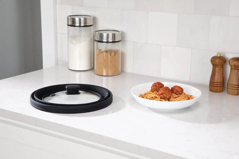 Mess Free Microwave Splatter Cover With Foldable Design next to spaghetti and meatballs on counter