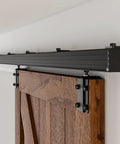 Rock Solid Heavy Duty Sliding Barn Door Track Box Rail Kit for Single Doors up to 330 Pounds 79.2 Inch Aluminum frame installed above wooden door.