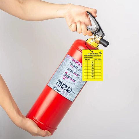 Person holding fire extinguisher with 4 Year Fire Extinguisher Inspection Tags 25 Pack Durable UV Waterproof