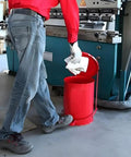 A person using a Heavy Duty Galvanized Steel Oily Waste Can Built Tough As Nails For Shop Use With Hands Free Kick Lever And Rust Proof Finish For Fire Safe Rag Pickup In Garages to dispose of shop towels.