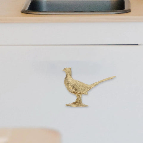 Top Shelf Brass Pheasant Drawer Knob With Rich Golden Finish, decorative bird hardware on white cabinet.