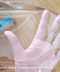 Crystal Clear Vinyl Round Tablecloth With Elastic Edge Fits 27 To 31 Inch Tables Spill Proof Waterproof, held by a hand