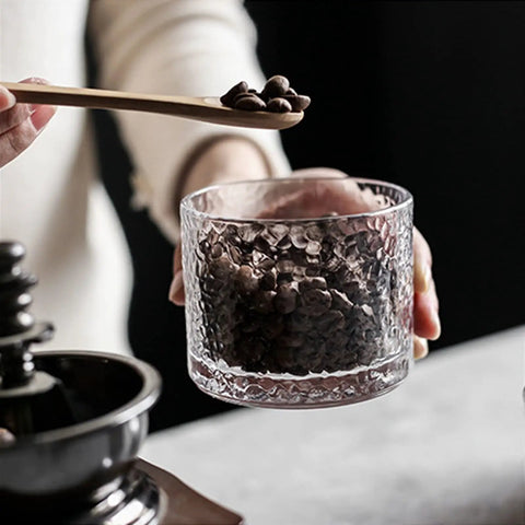 Top Shelf Airtight Glass Storage Jars 320 Milliliters With Durable Sealed Lids For Coffee Beans, held with coffee beans inside.