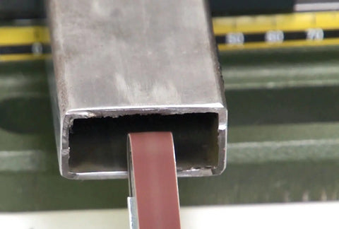 Beast Belt Sander For Finish Work And Detail Sanding on metal tube, showing 60 degree swivel head in action for precise sanding