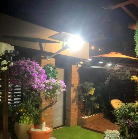 JUDYSSY Solar Floodlights illuminating a garden at night, highlighting flowers, plants, and outdoor decor.