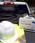 First Aid Kit 91324 in white plastic case with blue label; front view shows safety hard hat and hi-vis vest on a truck bed.