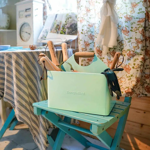 Metal Garden Tool Organizer Caddy With Four Compartments And Wooden Handle For Indoor And Outdoor Use Grab And Go Ready, Rust Resistant Garden Storage Box For Tools Green Caddy For Gardener Gift And Everyday Yard Cleanup on a blue chair.