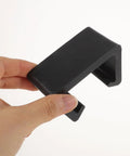 Hand holding a single black clip from 12 Pack Outdoor Patio Furniture Clips For Rattan And Wicker Sectional Sofas Sofa Clamps Fasteners