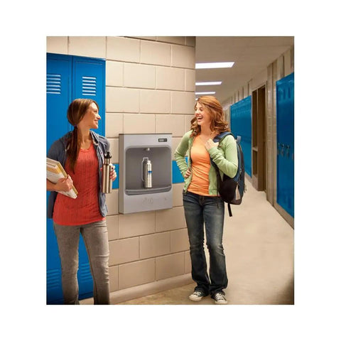 Two students chatting near a Heavy Duty Battery Powered Mechanical Bottle Filling Station With Filtered Stainless Surface Mount.