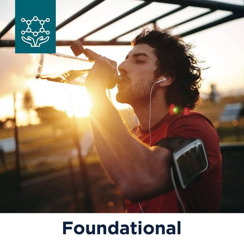 Person drinking water outdoors at sunset, wearing earphones and armband. "Foundational" text in frame. Workout setting.