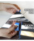 Hands peeling back liner of Daytime Privacy Window Film For Heat Control And Mirror Silver Tint Very Dark Level 5 36 Inch By 24 Foot Roll