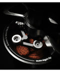Close-up of 58mm stainless steel magnetic WDT tool distributing coffee grounds for balanced saturation.