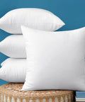 Set Of 4 18x18 Outdoor Pillow Inserts, Water Resistant Cushion Shams For Porch Swing displayed on woven stool