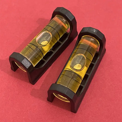 Close-up of two levels from Magnetic Gunsmithing Tools Kit With Level and Scope Mounting Leveler for Rifles on a red surface