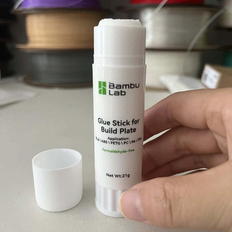 Hot Bed Glue Stick For 3D Printing Delivers Strong Bed Adhesion On A1 Mini P1 X1 Printers beside open cap, hand-held close-up