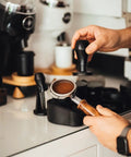 Person using Portafilter Holder And Tamping Station For Espresso, 304 stainless steel with silicone holder for 58mm portafilters.