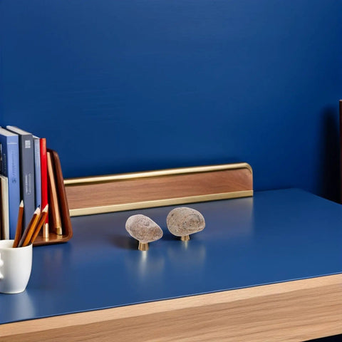 Dope Irregular Pebble Stone Cabinet Handles With Brass Base for furniture and home decor on a blue desk