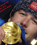 Person holding gold medal and wearing USA Olympic hat, text reads 'Happy Trampoline Endorsed by Olympic Gold Medalist Skier.'