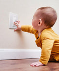 Childproof Light Switch Plate Covers 2 Pack White Safe Home Shield To Stop Little Ones And Curious Adults From Accidentally Flipping The Switch Easy Install Toggle Switch Shields shown being reached by a child