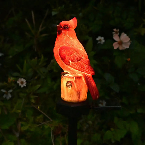 Red Bird Solar Light Garden Stake Figurine in garden glowing at night, weather-resistant for outdoor yard decor and memorial gift.
