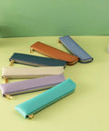 Assorted leather pencil cases with zippers, including Purple Leather Pencil Case For Adults Slim Soft Pen Bag With Zipper Minimalist Pencil Pouch Premium Leather Craft For Pros Ultra Lightweight Office And School Storage For Notes Drafts And Everyday Carry, arranged on green surface.