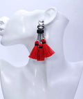 Red tassel earrings with black accents on a mannequin head, side view