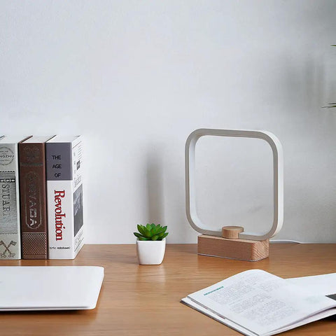 Cozy Minimalist Square Bedside Lamp With 3 Color Temperatures And Dimmable LED Lighting on a wooden desk next to books and a plant