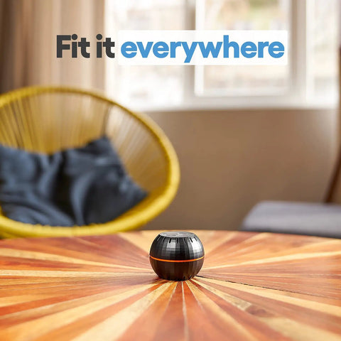 HT Black WiFi Temperature And Humidity Sensor For Smart Home Automation on a wooden table with chair in the background
