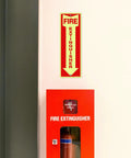 Heavy Duty Fire Extinguisher Signs 12 Pack Made From Rust Free Aluminum 12 By 4 Inch Glow In The Dark Waterproof Weatherproof Fade Resistant Two Pre Drilled Holes For Easy Indoor Outdoor Mounting installed on wall above fire extinguisher box.