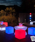 16-Inch Cordless LED Cube Light With Removable Panels glowing in red and blue outdoors at night, remote control visible.