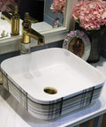 Premium Ceramic Vessel Sink, Snazzy Square Countertop Basin, with gold faucet and flowers, stylish above counter design.