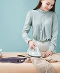 Woman ironing clothes on table with Heavy Duty 51.97 Inch High Temperature Steam Hose Replacement For Garment Steamer nearby.