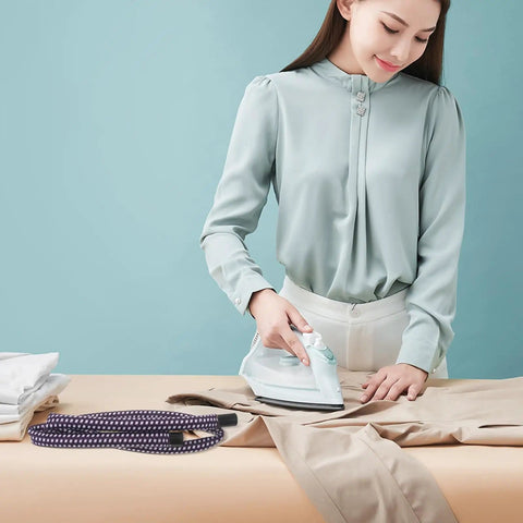 Woman ironing clothes on table with Heavy Duty 51.97 Inch High Temperature Steam Hose Replacement For Garment Steamer nearby.