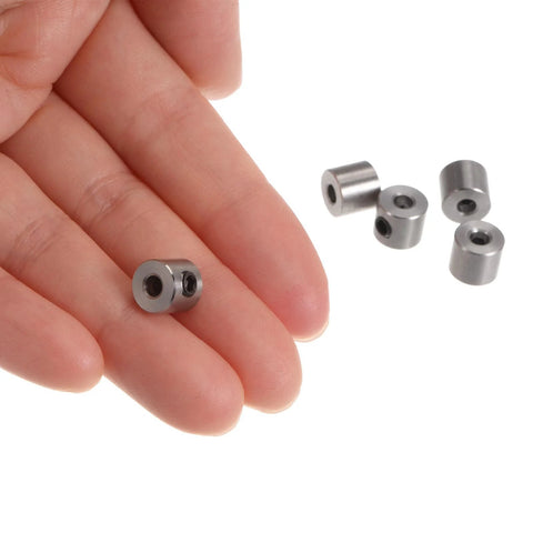 Six stainless steel shaft collars with set-screw holes, hand-held close-up