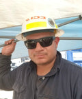 Man wearing Men's Safety Glasses With Smoke Lens, Matte Black Wraparound Frame, ANSI Z87 compliant sunglasses under a work hat.