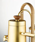 Top Shelf Belgian Siphon Coffee Maker With Stunning Gold Finish Built From Heavy Glass And Steel Frame Relies On Steam Heat And Gravity Action To Pull Silky Smooth Brews Fast Sick Flex For True Coffee Geeks Wanting Elite Taste At Home Or Work, featuring gold body and wood accent.