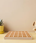 Top Tier Solid Wood Jewelry Tray Organizer Designed To Keep Your Bling Neatly Arranged In 36 Grids on a wooden table with a plant.
