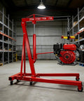 Easy Roll Three Ton Folding Hydraulic Engine Hoist packs a nine ton pump lifting a red engine in a garage setting.