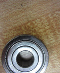 Close-up of a 6200Z single-shielded deep-groove ball bearing 10 mm ID x 30 mm OD x 9 mm width on a wooden surface