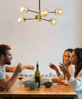 Six Light Amber Glass Globe Sputnik Chandelier With Dope Black And Gold Industrial Pendant Lighting over a dining table scene