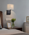 Hardwired Modern White Fabric Wall Sconce Dual Switch On Off Indoor Lighting for Bedroom beside a bed with nightstand
