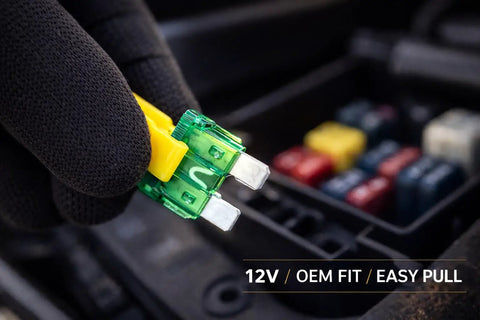 60 Piece Tough As Nails Led Blade Fuse Assortment showing green and yellow fuses held with a gloved hand for automotive use.