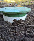Pop Up Drainage Emitter With Elbow For 4 Inch Drain Pipe in-ground installation with green cap, lawn surface view