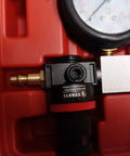 Cylinder leak-down tester for engines; red housing with brass connector and visible pressure gauge (close-up view).